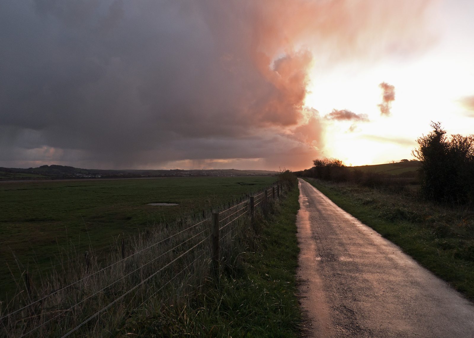 Chemin de campagne sous un ciel d'orage au lever du soleil : la lumière perce les nuages d'automne, métaphore des turbulences traversées avec sens